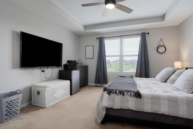 bedroom featuring a ceiling fan, baseboards, light colored carpet, and a raised ceiling