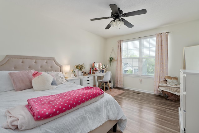 bedroom with visible vents, baseboards, ceiling fan, and wood finished floors