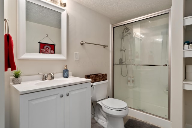 bathroom featuring vanity, toilet, a textured ceiling, and a stall shower