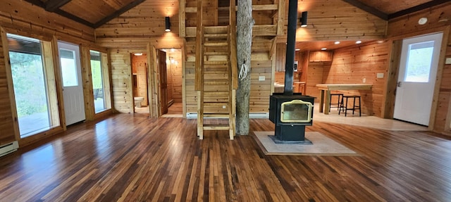 unfurnished living room featuring a wood stove, wood walls, wood ceiling, and wood finished floors