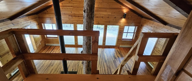 interior space with a baseboard heating unit, wooden walls, hardwood / wood-style flooring, and lofted ceiling with beams