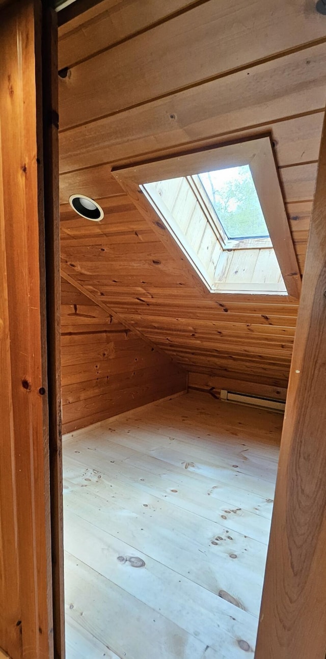 additional living space with wood walls and vaulted ceiling with skylight