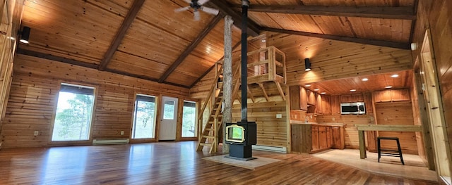 unfurnished living room with high vaulted ceiling, wood walls, a wood stove, wooden ceiling, and a baseboard radiator