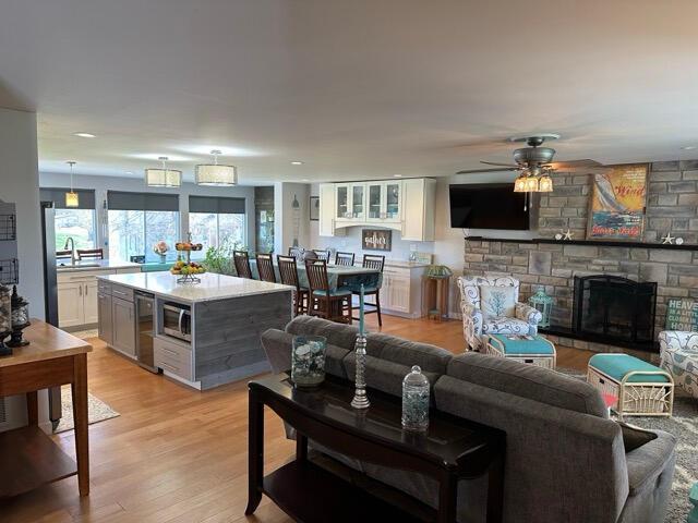 living room featuring a ceiling fan, light wood-style flooring, and a fireplace