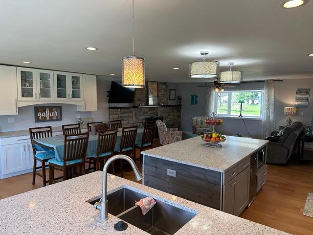 kitchen with light stone counters, a sink, wood finished floors, and white cabinets
