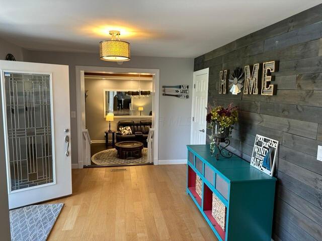 hall with baseboards, wood finished floors, and an accent wall