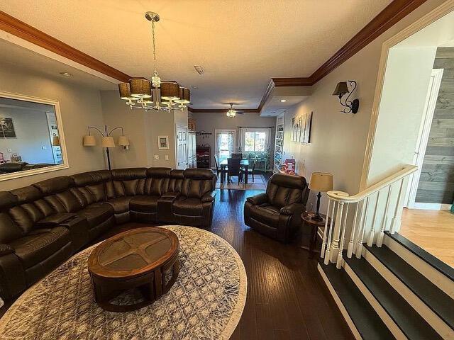 living area featuring ornamental molding, ceiling fan with notable chandelier, and wood finished floors