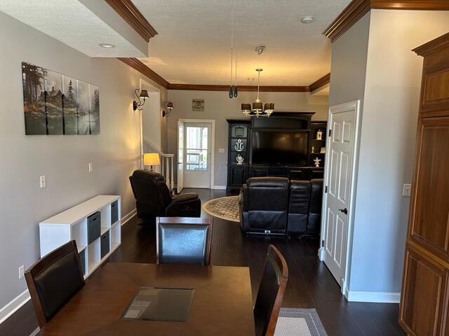 dining room featuring baseboards, a chandelier, ornamental molding, and dark wood-type flooring