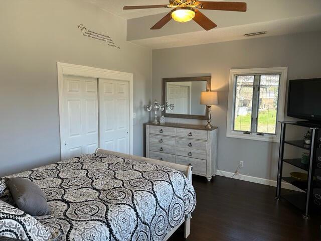bedroom with visible vents, a closet, baseboards, a ceiling fan, and dark wood finished floors