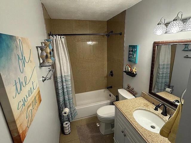 full bathroom featuring a textured ceiling, tile patterned flooring, vanity, toilet, and shower / bathtub combination with curtain