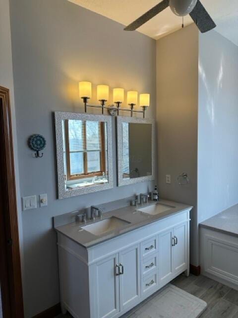 full bath featuring double vanity, a ceiling fan, a sink, and wood finished floors