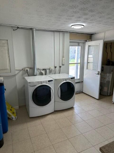 washroom featuring washing machine and clothes dryer, laundry area, light tile patterned floors, and water heater