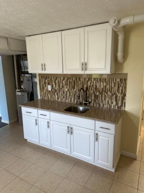 kitchen with white cabinets, baseboards, decorative backsplash, and a sink