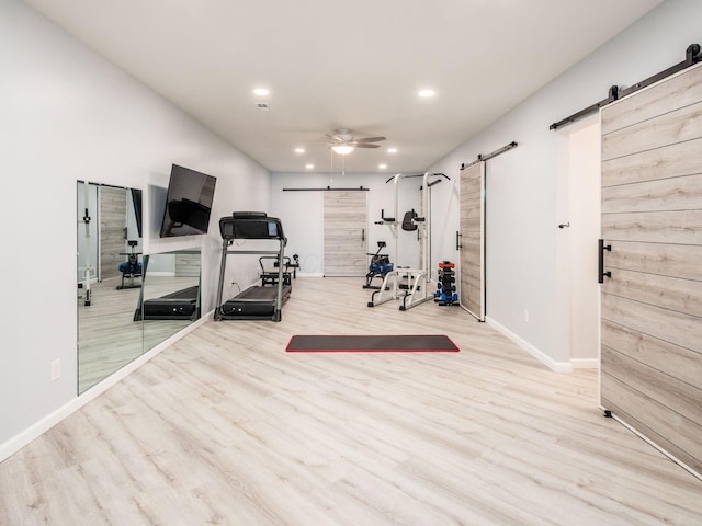exercise area with recessed lighting, a barn door, baseboards, ceiling fan, and wood finished floors