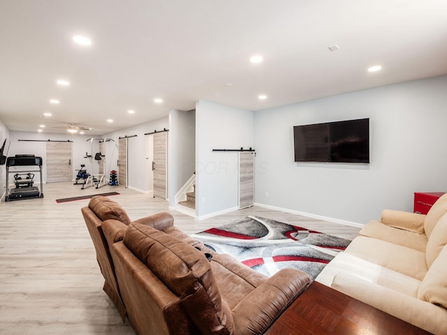 living area with a barn door, recessed lighting, ceiling fan, light wood-style flooring, and baseboards