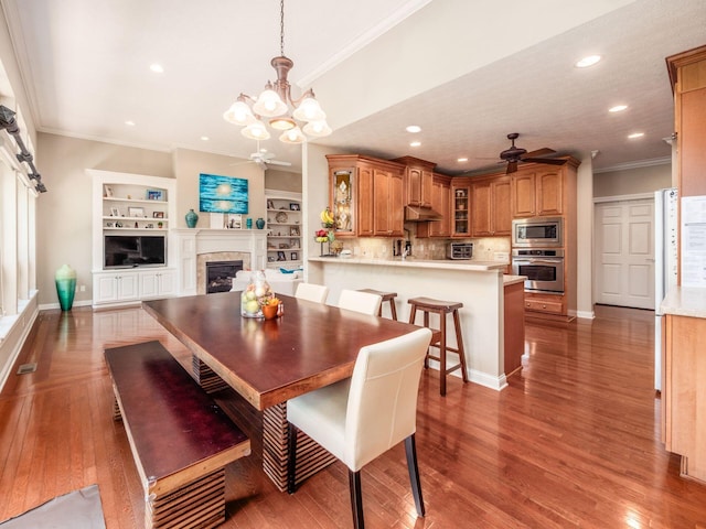 dining room with crown molding, a fireplace, ceiling fan with notable chandelier, and recessed lighting