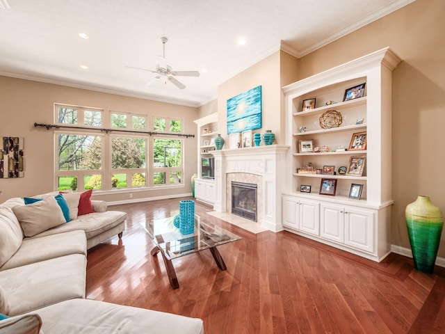 living room featuring baseboards, ornamental molding, ceiling fan, light wood-style floors, and a fireplace
