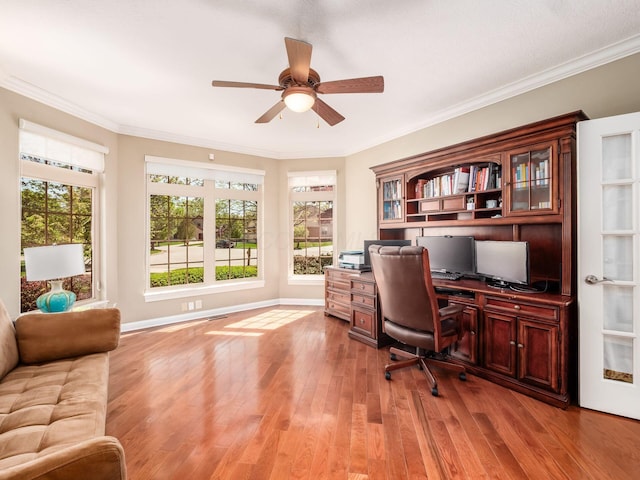 office space featuring a ceiling fan, light wood-style flooring, baseboards, ornamental molding, and built in desk