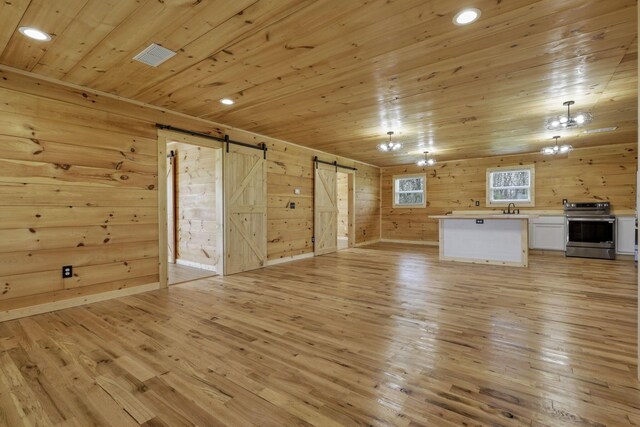 7435 Baltimore Somerset Rd NE, Thornville, OH 43076 - unfurnished living room featuring wood walls, light wood-style floors, a barn door, wood ceiling, and a sink