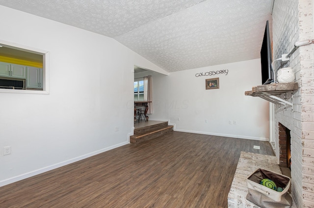 unfurnished living room featuring a brick fireplace, a textured ceiling, baseboards, lofted ceiling, and dark wood-style floors