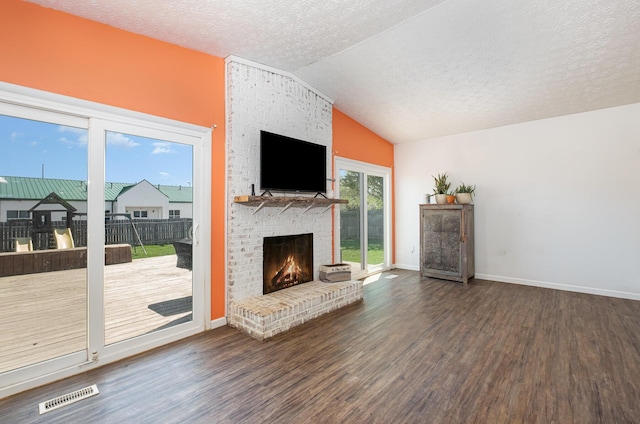 living room with visible vents, a brick fireplace, wood finished floors, a textured ceiling, and vaulted ceiling