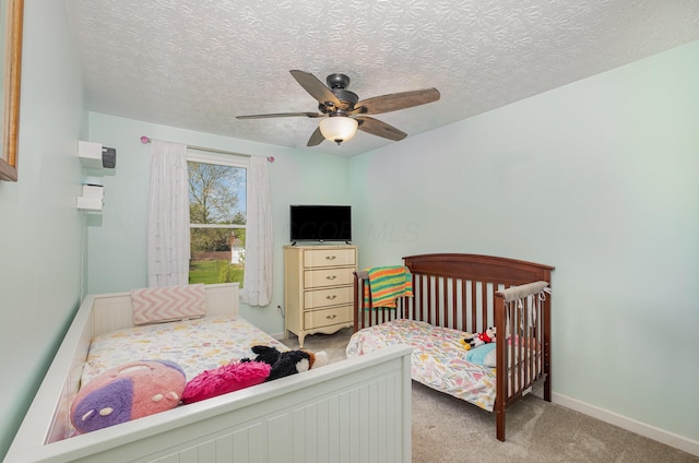 bedroom with baseboards, ceiling fan, carpet, and a textured ceiling