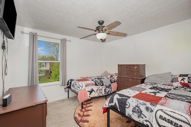 bedroom featuring baseboards, a textured ceiling, light carpet, and ceiling fan