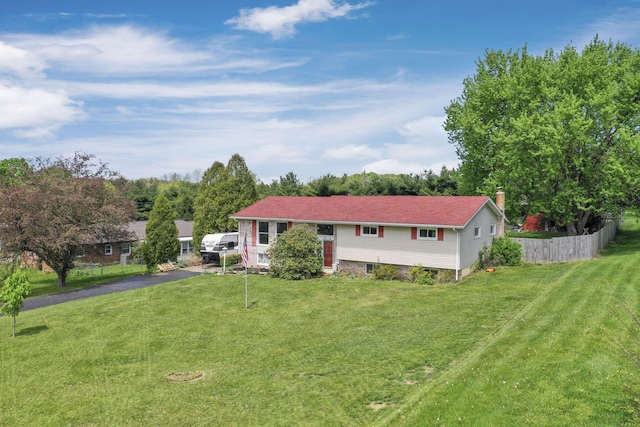 view of front of property featuring a front lawn, aphalt driveway, fence, and a chimney