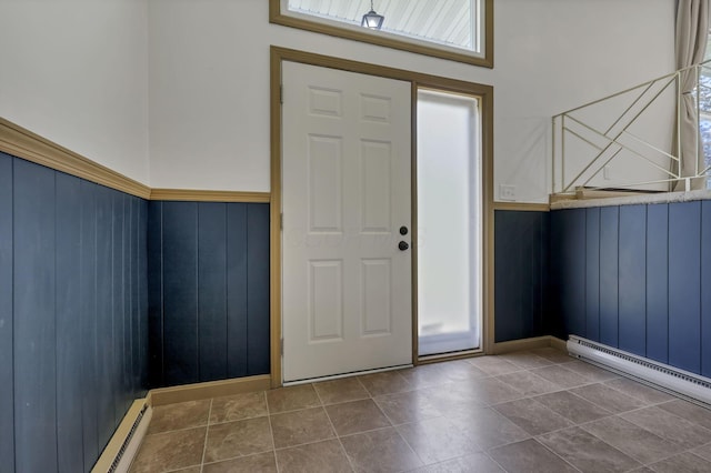 foyer with wooden walls, a baseboard radiator, baseboard heating, and a wainscoted wall