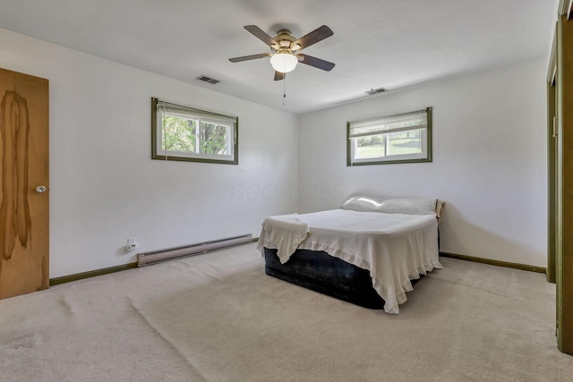 carpeted bedroom featuring visible vents, baseboards, a baseboard heating unit, and multiple windows
