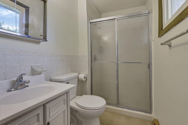 full bathroom with tile walls, wainscoting, a stall shower, vanity, and toilet