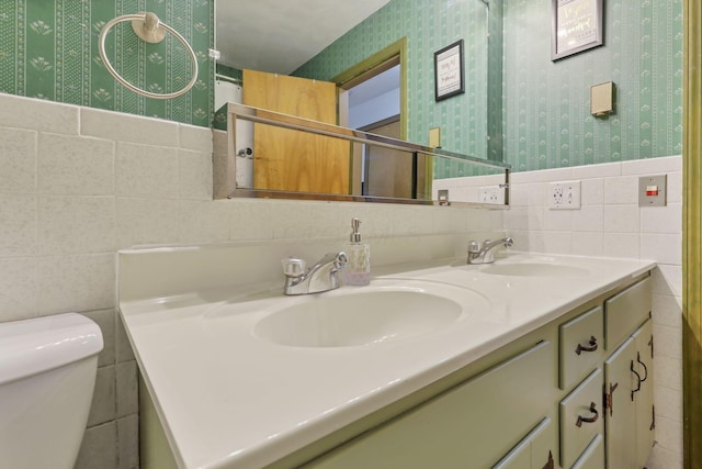 bathroom featuring wallpapered walls, tile walls, and a sink