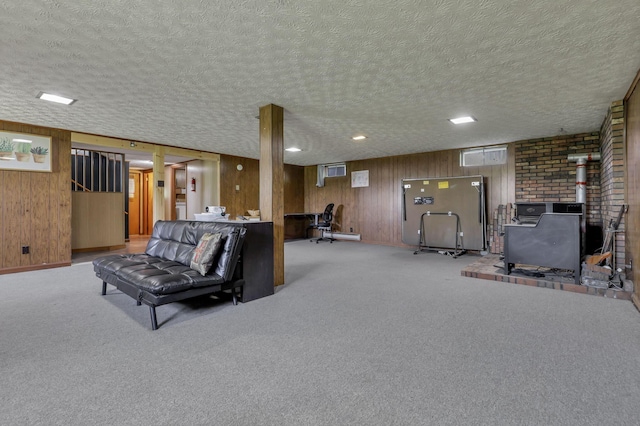 living area featuring a wood stove, a textured ceiling, carpet flooring, and wood walls