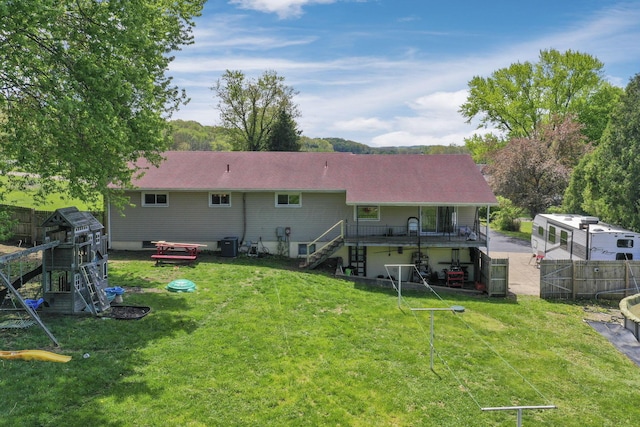 rear view of house with a fenced backyard, central AC unit, a lawn, and stairway