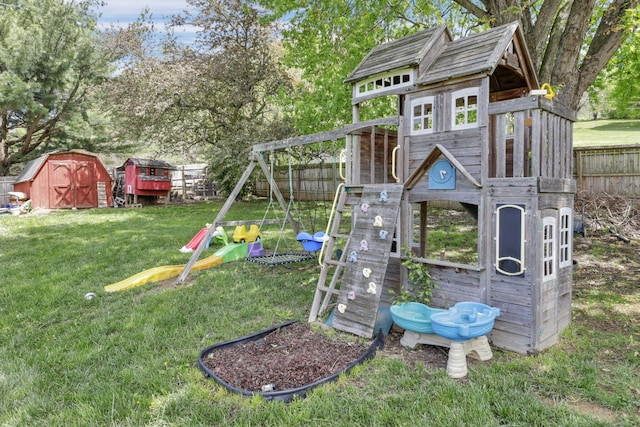 view of jungle gym featuring a lawn, fence, an outbuilding, and a storage unit