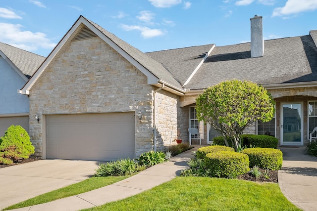 multi unit property with driveway, a chimney, roof with shingles, an attached garage, and stone siding