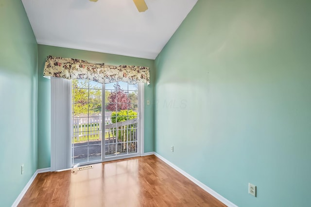 empty room with a ceiling fan, baseboards, vaulted ceiling, and wood finished floors