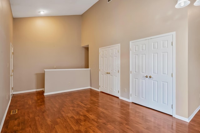 unfurnished bedroom featuring baseboards, visible vents, two closets, and a towering ceiling