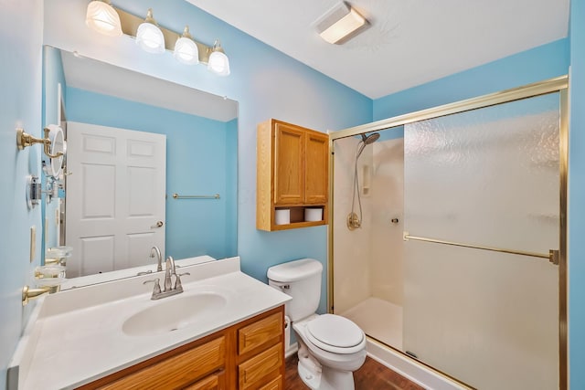 bathroom with vanity, toilet, wood finished floors, and a stall shower