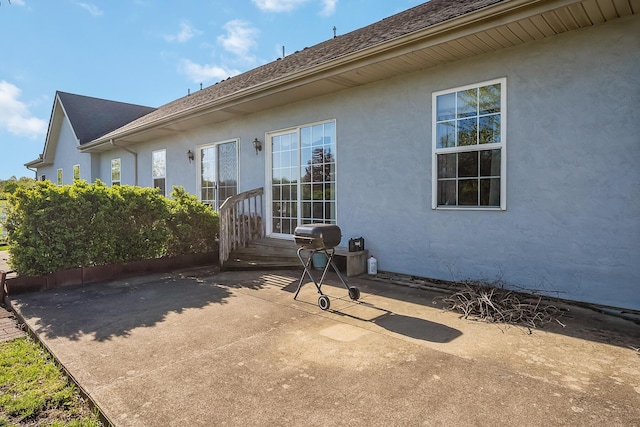 back of house with a patio, a shingled roof, and stucco siding
