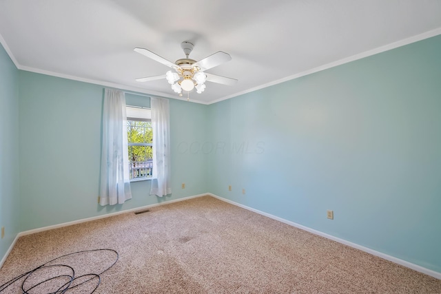 carpeted spare room featuring visible vents, baseboards, and crown molding