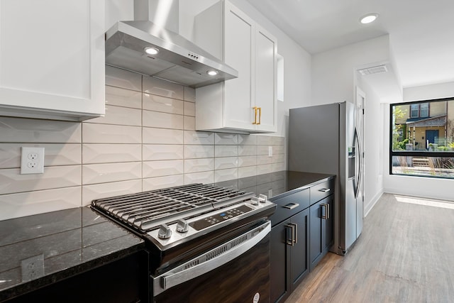kitchen featuring visible vents, light wood-style floors, wall chimney range hood, white cabinets, and appliances with stainless steel finishes