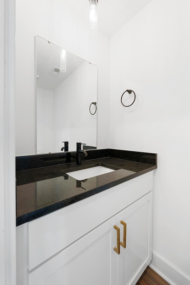bathroom featuring vanity, baseboards, wood finished floors, and visible vents