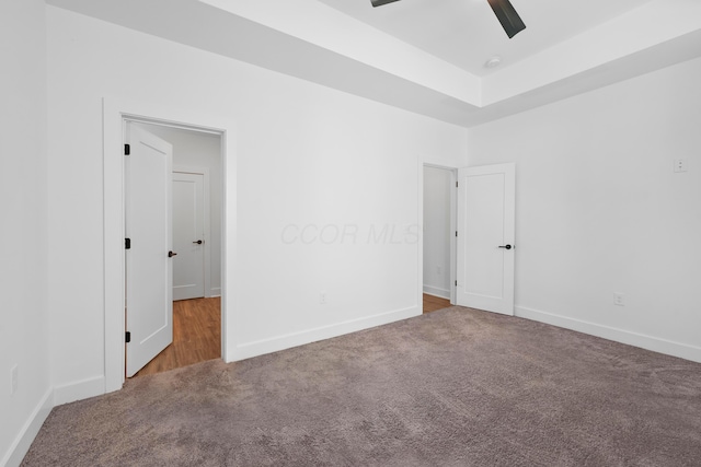 carpeted empty room featuring ceiling fan and baseboards