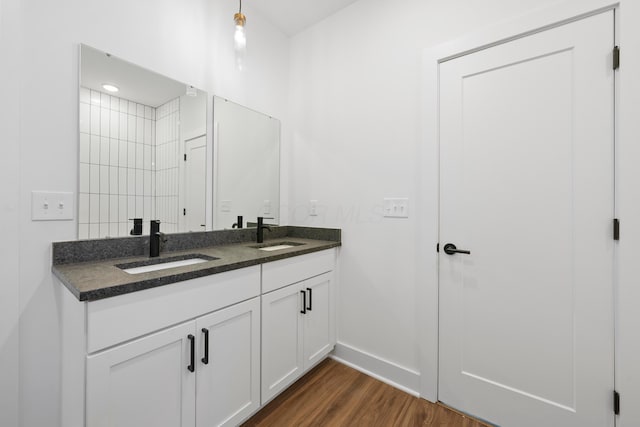 full bathroom with double vanity, baseboards, a sink, and wood finished floors