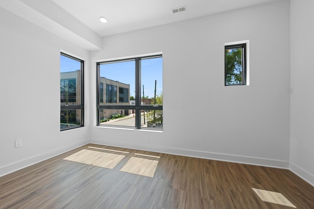 spare room featuring baseboards, visible vents, and wood finished floors