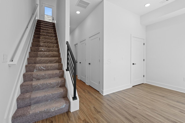 stairway with baseboards, recessed lighting, wood finished floors, and visible vents
