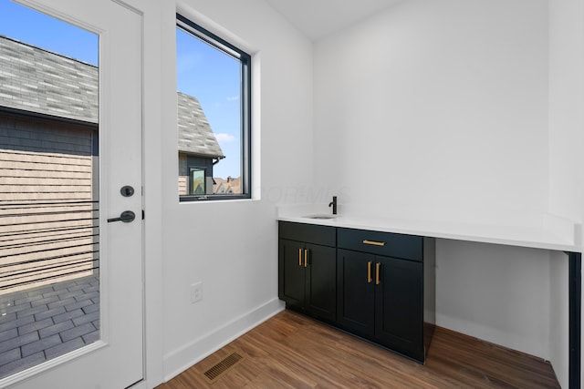 doorway featuring baseboards, a wealth of natural light, dark wood-type flooring, and visible vents