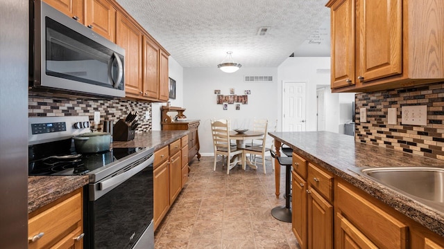 42 Ellington Commons Ln, Granville, OH 43023 - kitchen with appliances with stainless steel finishes, brown cabinets, dark countertops, and tasteful backsplash