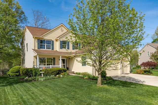 traditional-style house featuring a porch, an attached garage, driveway, and a front lawn